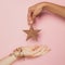 Christmas holiday concept. Black and white friends woman hands with gold Xmas decoration star on pink background