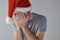 Christmas holiday depression, sad sulking man with Santa Claus hat covering face with his hands and crying alone