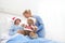 Christmas holiday in hospital happy child lying in bed with Santa Claus hat and nurse dressing a teddy bear