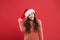 Christmas holiday invitation concept. Playful cutie. Adorable girl with long curly hair wear santa claus hat red