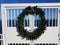 Christmas or holiday wreath on white fence or door and water