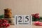 Christmas home concept. Wooden calendar dated December 25, chocolate cookies on wooden stand, red berries, and Christmas tree