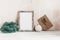 Christmas Home Decor. Retro styled. Blank portrait frame, fir branch, Christmas balls and craft envelope. Old white wooden table