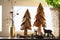 Christmas home decoration. Artificial wooden Christmas trees, fir cones and deer figurines on the window in the interior