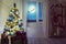 Christmas home room with tree and moon lighting in window.