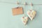 Christmas image of fabric hearts and empty card for adding text hanging on rope in front of blue wooden background. retro filtered