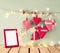 Christmas image of fabric red hearts and blank frame, garland lights, hanging on rope in front of blue wooden background