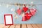 Christmas image of fabric red hearts and blank frame, garland lights, hanging on rope in front of blue wooden background