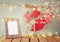 Christmas image of fabric red hearts and blank frame, garland lights, hanging on rope in front of blue wooden background