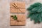 Christmas invitation or greeting letters in a craft envelope, spruce branch, beige rustic background. Top view, flat lay