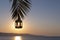 Christmas lantern on palm tree, background rising sun over sea. Christmas, New Years holiday. Greeting card, copy space