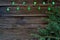 Christmas lights on a wooden background with free space. In the background of twigs Christmas trees.