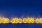 Christmas lights yellow stars burn on dark ultramarine wooden background.