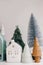 Christmas little houses and trees on white background. Festive modern decor. Happy holidays. Miniature cozy village, ceramic
