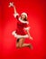 Christmas, x-mas, winter, concept - smiling woman in santa helper hat with gift box, happiness jump for joy over red