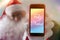 Christmas message in portuguese: Feliz Natal from Santa Claus or Saint Nicholas showing cell phone screen. Blurred background