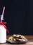 Christmas milk and chocolate cookies on wooden table over black