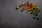 Christmas minimalism composition. New Year`s green and orange decorations in the form of flowers and balls on a dark bac