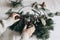 Christmas moody still life. Closeup of women hands crafting advent floral hoop wreath. Garland of fir, eucalyptus. Pine