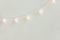 Christmas New Year Background. Diagonal Hanging Pastel Golden Cotton Balls Garland White Wall Background. Scandinavian Style