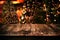 Christmas and New year background with empty dark wooden deck table over christmas tree and blurred light bokeh