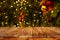 Christmas and New year background with empty dark wooden deck table over christmas tree and blurred light bokeh.