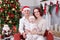 Christmas or New year celebration. Portrait of cheerful young family of three people near the Christmas tree with xmas gifts. A fi