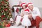 Christmas or New year celebration. Portrait of cheerful young family of three people near the Christmas tree with xmas gifts. A fi