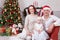 Christmas or New year celebration. Portrait of cheerful young family of three people near the Christmas tree with xmas gifts. A fi