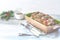 Christmas and New Year composition with delicious baked meat with cranberry and spices, spruce branches, cutlery on light gray