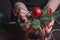 Christmas or New Year concept, in female hands a red burning candle and hellebore, selective focus