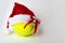 Christmas and New Year concept with Santa hat on tennis ball on gray background.
