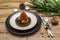 Christmas and New Year dinner place setting. Sweet snack, fir tree branch, candles, cones, ceramic plates, fork and knife. Winter