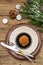 Christmas and New Year dinner place setting. Sweet snack, fir tree branch, candles, cones, ceramic plates, fork and knife. Winter