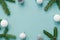 Christmas or New Year festive background with spruce branches, sequins, cones and white Christmas tree toys on mint paper surface,