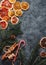 Christmas or New Year flat lay home decor, dry oranges, cinnamon, candies and fir branches on concrete background. Cozy winter hom