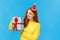 Christmas, new year and holidays concept. Attractive lovely redhead woman, girlfriend in cute hat holding wrapped gift