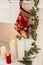 Christmas or New Year red knitted stocking with snowman, burning candles, decorative fur-tree branches and electric