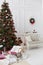 Christmas or New Year room with dressed Christmas tree with red Christmas balls and candles, decorative wooden sleigh covered with