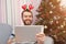 Christmas online congratulations. Smiling man near chrstmas tree using tablet for video call friends and parents