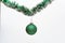 Christmas ornament concept. Ball with glamorous ornaments hang on shimmering green tinsel. Tinsel with pinned christmas