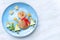 Christmas pancake shaped like snowman with fresh vegetables blue plate on wooden white table. Christmas fun food for