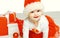 Christmas and people concept - cute smiling child in santa red hat with boxes gifts