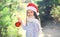 Christmas and people concept - little child in santa red hat with ball
