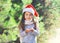 Christmas and people concept - little girl child in santa red hat blowing snow in hands