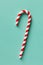 Christmas peppermint candy cane on pastel turquoise background. Festive minimal style flat lay. For greeting card, invitation,