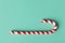 Christmas peppermint candy cane on pastel turquoise background. Festive minimal style flat lay. Mockup with copy space for