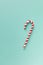 Christmas peppermint candy cane on pastel turquoise background. Festive minimal style flat lay. Mockup with copy space for