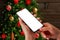 Christmas phone mockup concept. Smart phone in woman hands front off Christmas tree