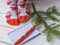 A Christmas photo with feminine feet in bright red socks, a fir twig, a note book and a pencil on a white wooden floor